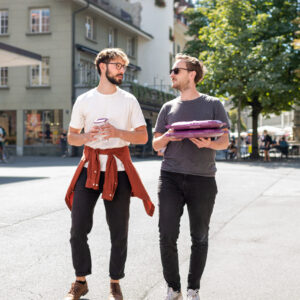 Zwei Männer laufen gemeinsam durch die Stadt, einer hält einen reCIRCLE ISY in der Hand der andere eine reCIRCLE Pizza BOX