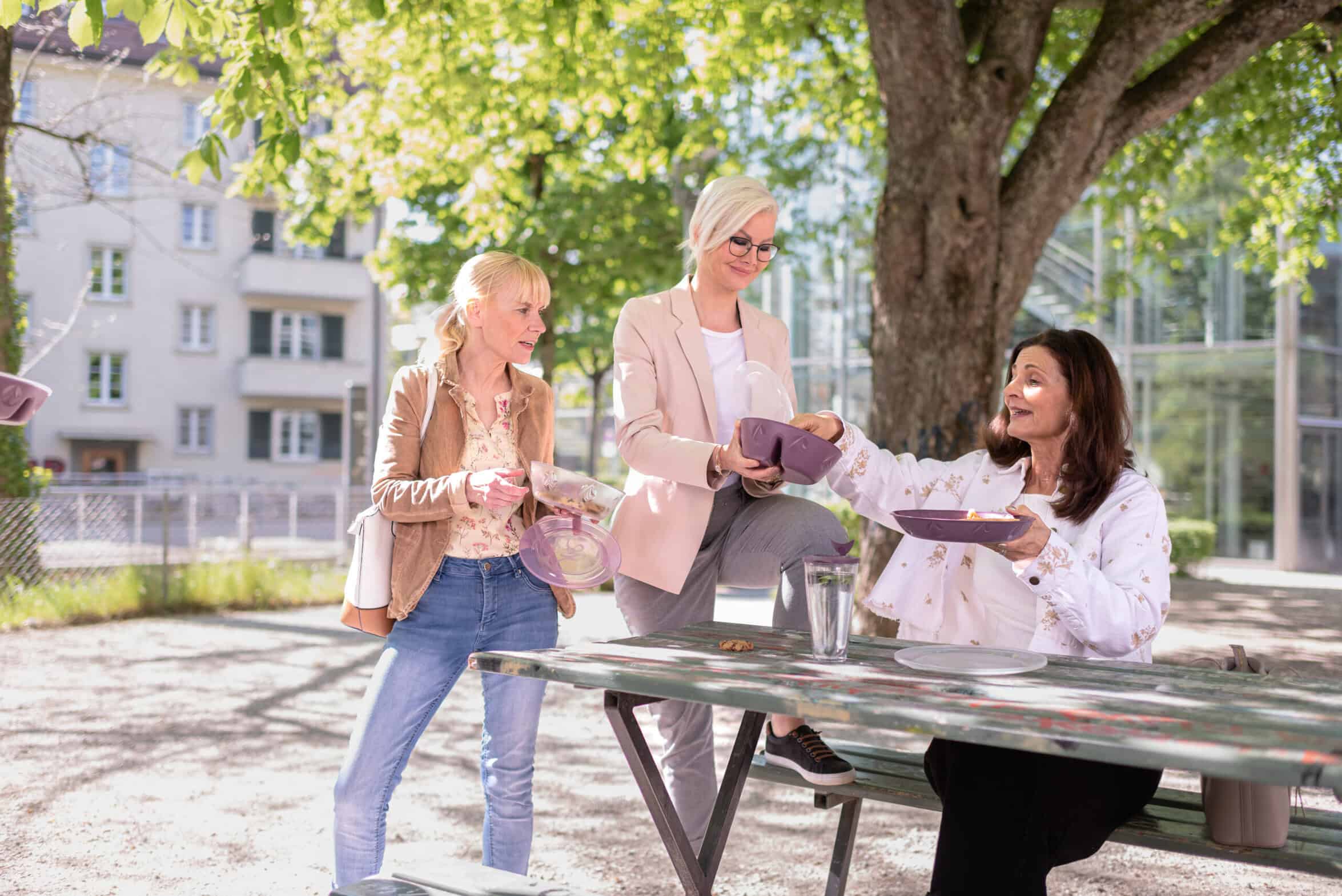 Drei Freundinnen sind im Park und teilen sich was zu essen